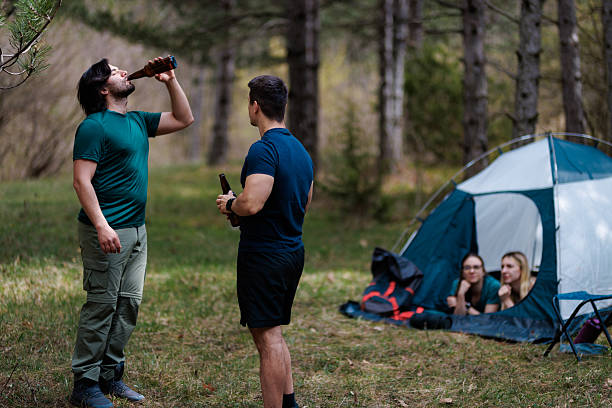 istock Friends enjoy a camping trip together in the forest while sharing drinks and relaxation near their tent on a sunny day 2236693140