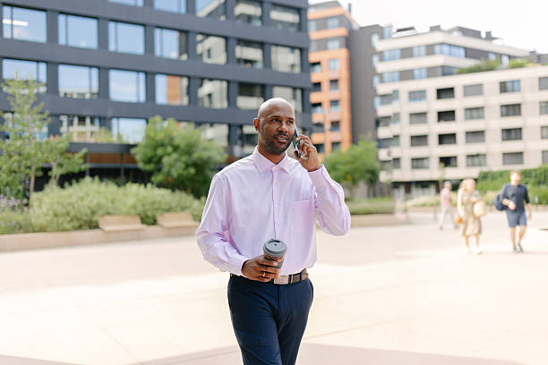 Stylish man walking with phone and coffee in hand