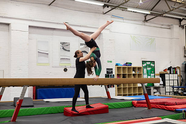istock Gymnast Practicing on the Balance Beam with Trainer 2236695100