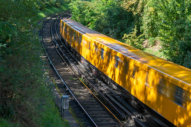 Subway train bathed in golden morning light approaches station, curving tracks lead into distance, warm sunrise glow reflecting on rails, urban commute in atmospheric dawn