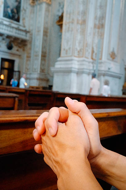 istock a man prays with clasped hands in a church 2236699800