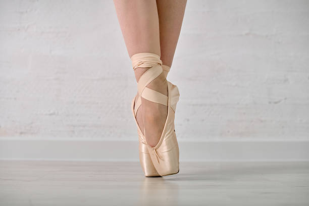 istock Ballet pointe shoes and feet on light floor 2236699965