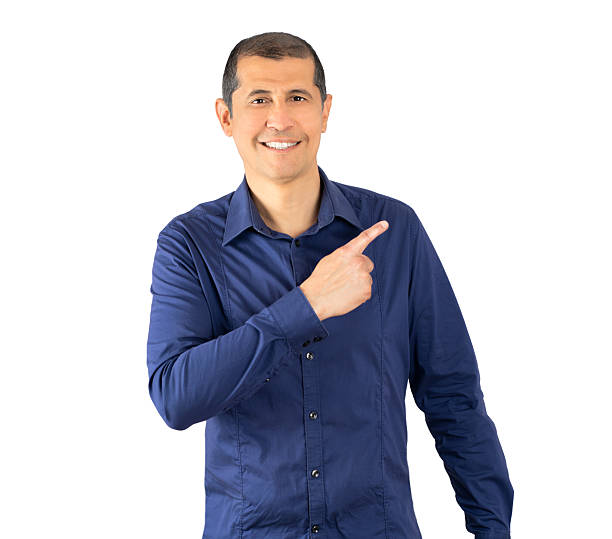 Handsome hispanic man wearing casual blue shirt over white background. Surprised pointing with finger to the side, open mouth amazed expression.