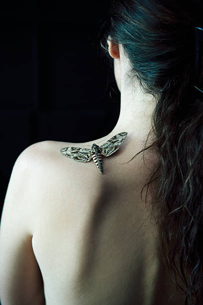 istock Butterfly sitting on woman shoulder close-up over dark background 2236700939