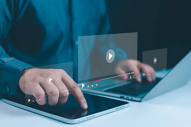 istock Close-up of hands using tablet and laptop with futuristic video streaming interface, symbolizing online learning, digital media, modern technology, and e-learning for education and business. 2236702139