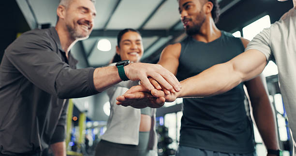 Fitness, people or group with hands together at gym for exercise support, victory or workout goals. Happy, athlete and teamwork with huddle at sports club for training milestone or wellness community