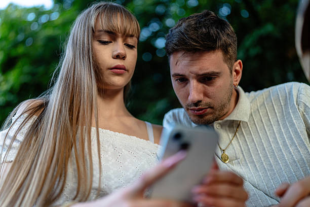 istock Focused young couple looking at a phone outdoors on a relaxing day 2236708882