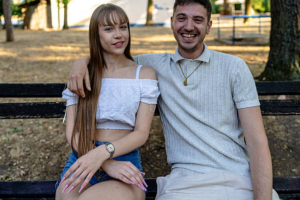 istock Smiling couple sitting on a park bench enjoying a bright sunny day 2236709656