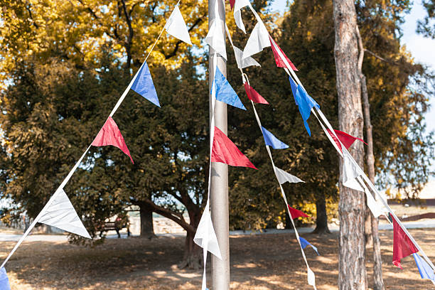 istock Triangular blue, white and red flags on a ribbon against a autumn park or natural backdrop. Concept for a holiday, festival or birthday party. 2236710734