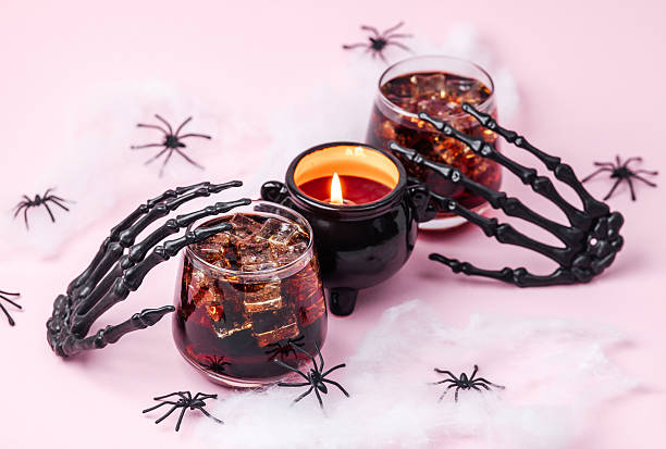 istock Creepy Halloween skeleton hands hold dark drinks with ice near cauldron candle with spiders 2236710826