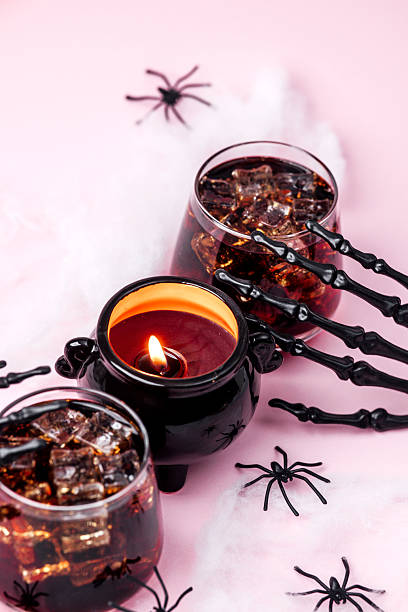 istock Halloween drink with spooky skeleton hands, cauldron candle, and plastic spiders on pink background 2236710827