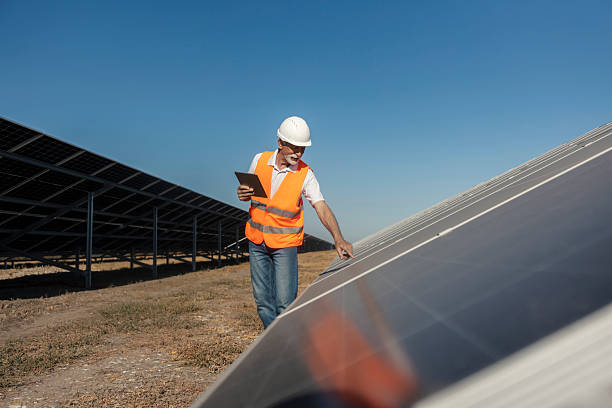 istock Senior Worker Inspects Solar Panels with Tablet in Hand on a Sunny Day 2236711481