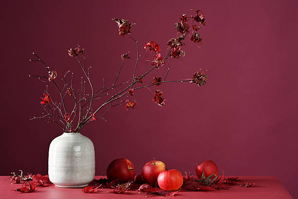 Autumnal decoration of maple branches and red apples on purple background