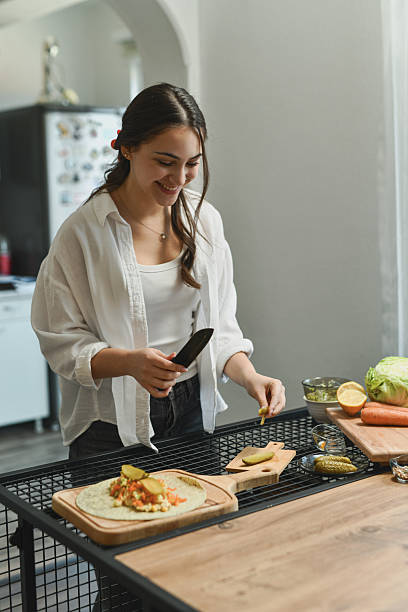 istock Smiling Female Slicing Pickles And Adding Them To Assembled Tortilla 2236718746
