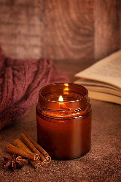 Cozy candlelit scene with cinnamon, anise spices, knitted sweater and opened book