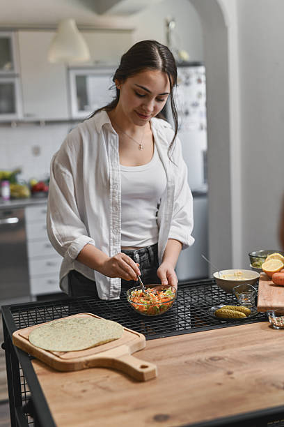 istock Woman Preparing Fresh Salad In Bowl Before Wrapping It Neatly Inside Tortilla 2236719035