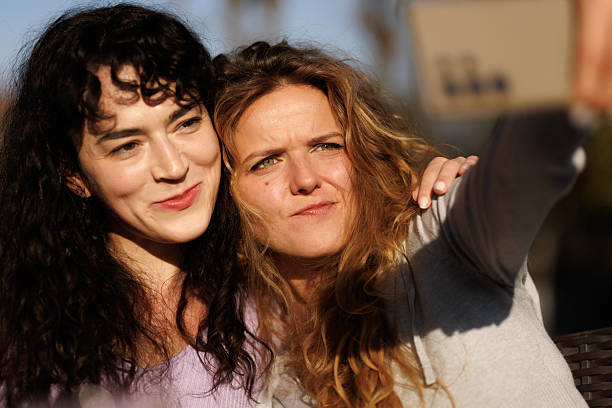 istock Two women enjoy a sunny afternoon while taking a selfie in a vibrant outdoor setting with soft sunlight illuminating their joyful expressions 2236719243