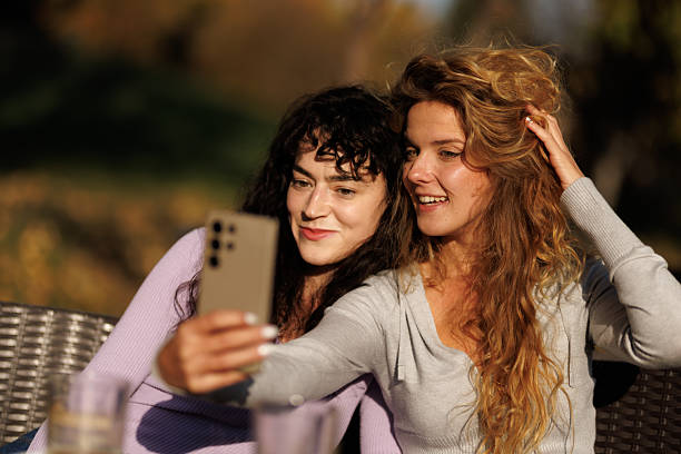 istock Two friends enjoy a sunny afternoon taking selfies outdoors while sitting on a comfortable couch surrounded by nature 2236719249