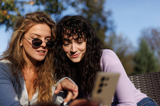istock Friends sharing moments outdoors while enjoying a sunny day, capturing memories and smiles on a digital device in a relaxed setting 2236719288