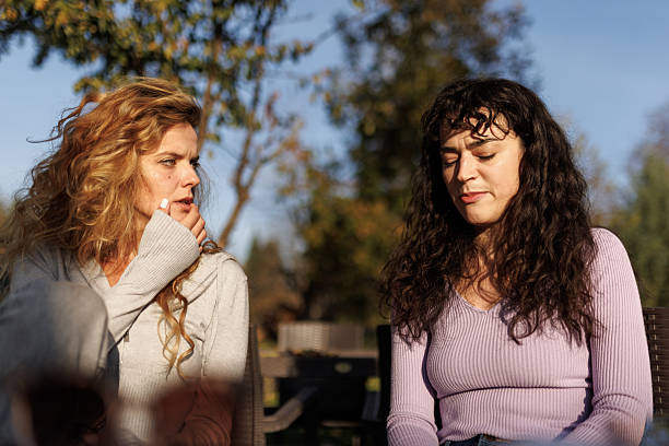 istock Two women engaged in conversation outdoors with sunlight filtering through trees in an afternoon setting 2236719289