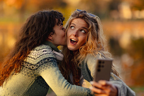 istock Friends enjoying a joyful moment while taking a selfie outdoors during autumn as leaves change color by the water's edge in a tranquil setting 2236719311