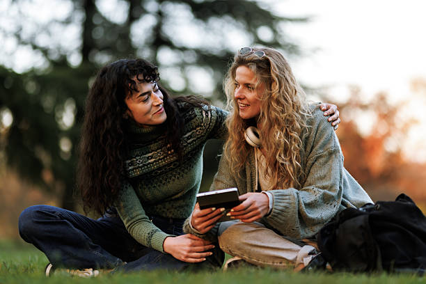 istock Two friends enjoying a relaxed afternoon in a park while sharing stories and laughter, surrounded by nature as the sun sets in the background 2236719349
