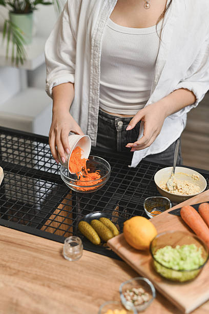 istock Female Adding Shredded Carrot To Salad Bowl While Preparing Nutritious Lunch 2236720956