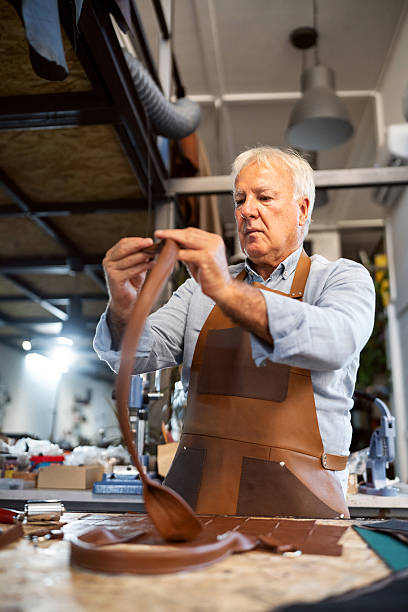 istock Senior craftsman working on a handcrafted leather handbag in workshop 2236722356