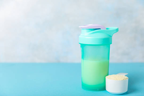 istock Protein shake with protein powder on a colored background. The powder is mixed with water or milk. A dietary supplement for a balanced diet. Whey protein. Fitness and gym diet nutrition. 2236722936