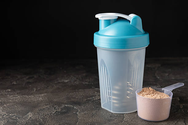 istock Protein shake with protein powder on a colored background. The powder is mixed with water or milk. A dietary supplement for a balanced diet. Whey protein. Fitness and gym diet nutrition. 2236722982