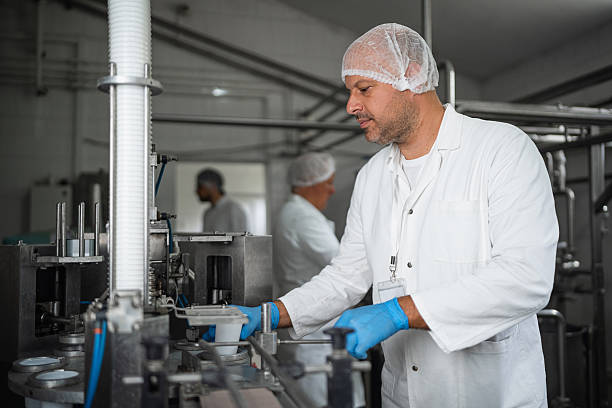 istock Worker in dairy processing plant operating equipment with safety gear 2236724533