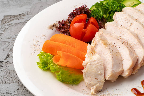 Roast chicken fillets and vegetables on gray background, close up