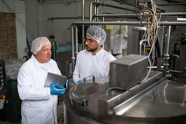 istock Workers in a milk processing plant discussing operations near industrial equipment 2236726152