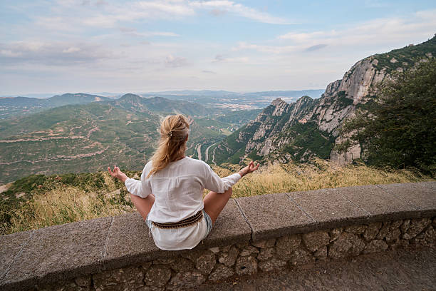 istock Woman meditating on mountain top enjoying nature view 2236730658