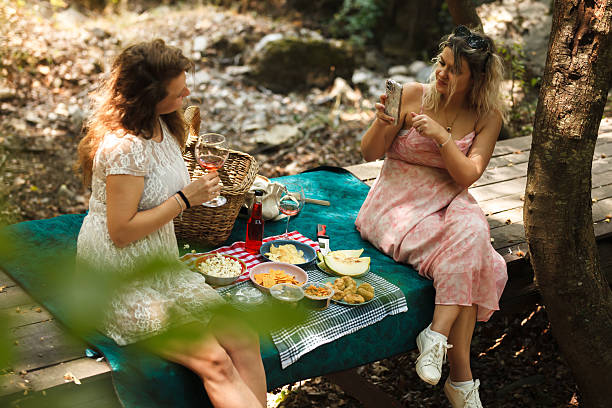 istock Two friends enjoy a picnic in a tranquil forest surrounded by nature, sharing delicious snacks and drinks during a sunny afternoon 2236736040