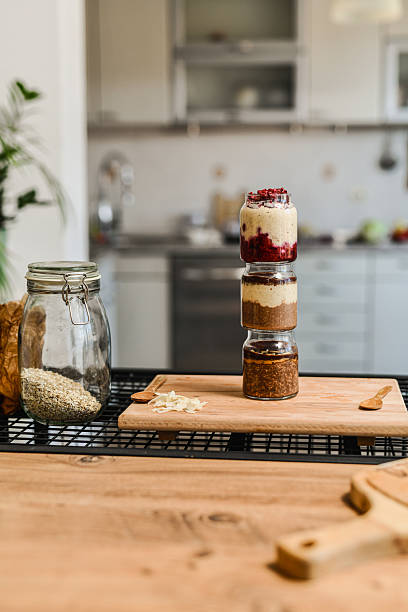 Stacked Jars Of Various Flavored Overnight Oats Arranged Vertically On Dining Table