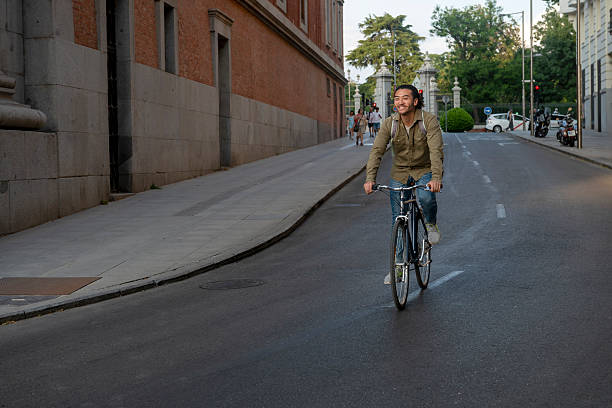 istock Young man smiling and riding a bicycle in the city 2236736991
