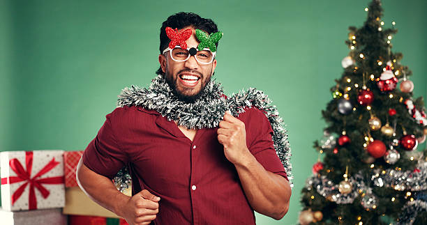 istock Christmas, excited and man dance in studio for celebration at festive event on green background. Xmas sunglasses, happiness or person moving with portrait, holiday tradition or laugh with party music 2236736996