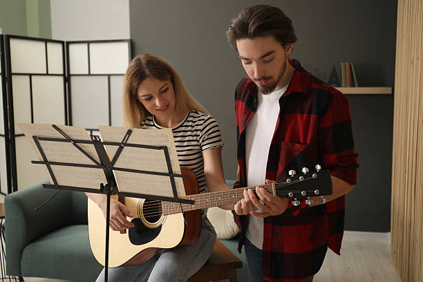 istock Tutor teaching woman to play guitar indoors 2236737615
