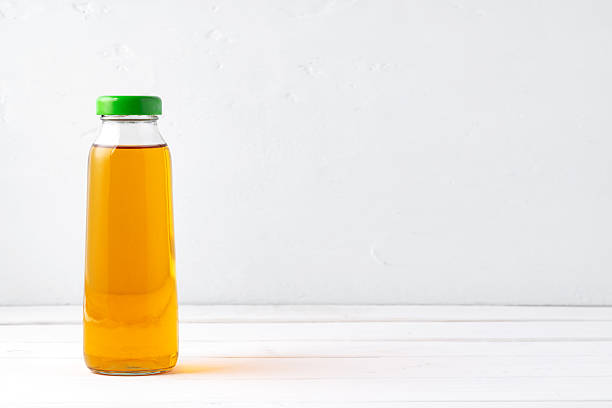 Small glass bottle of fresh juice on white background, close up