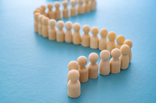 istock Wooden figures in a row behind another piece, on a blue surface. 2236737717