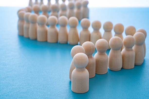 istock Wooden figures in a row behind another piece, on a blue surface. 2236737725