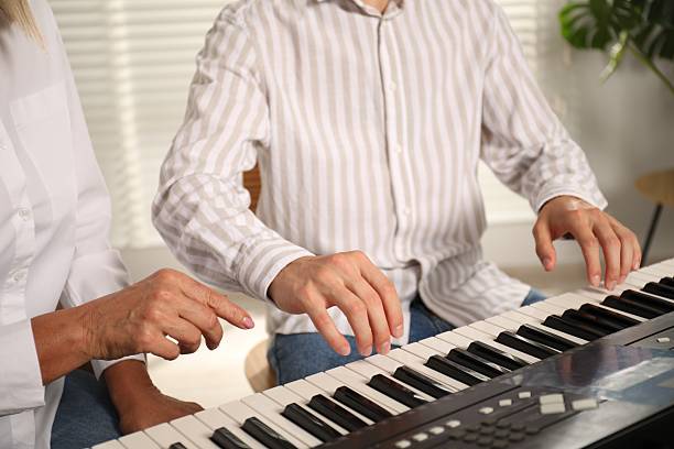 istock Tutor teaching man to play piano indoors, closeup 2236737901