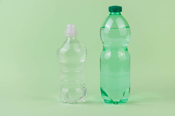 Healthy hydration concept with green apple and clear green bottles on light green backdrop