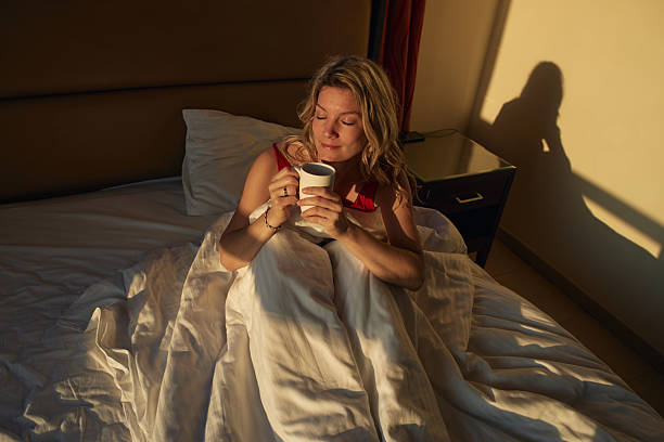 istock Woman enjoying morning coffee in bed with sunlight 2236740907