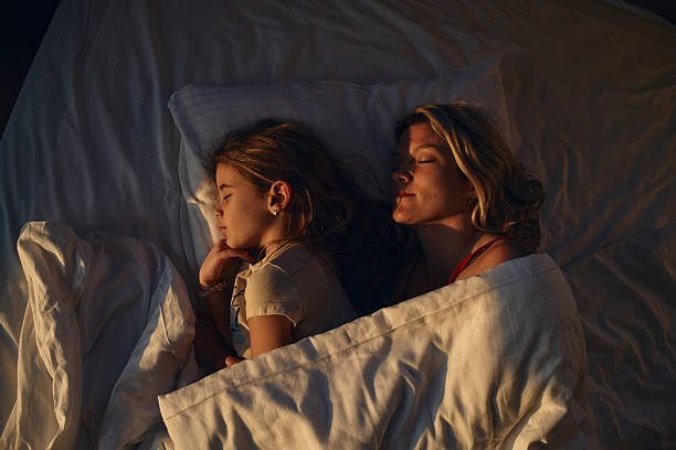 istock Mother and daughter sleeping peacefully in bed together 2236741182