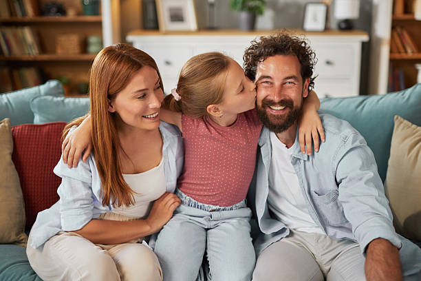 istock Daughter kissing father while sitting on sofa with mother at home 2236741373