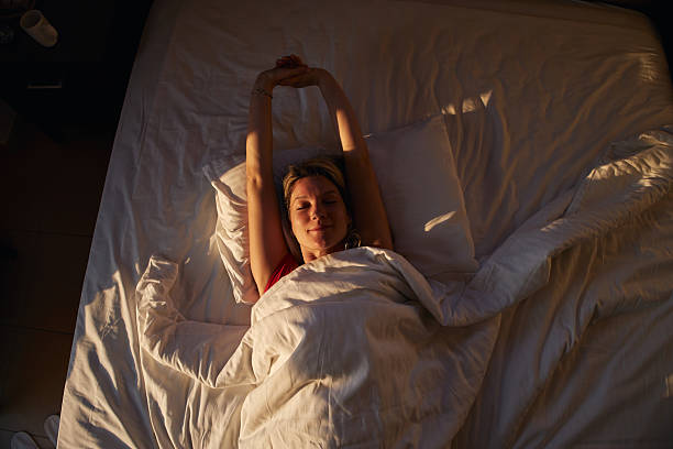 istock Woman waking up stretching in morning sunlight bed 2236741534