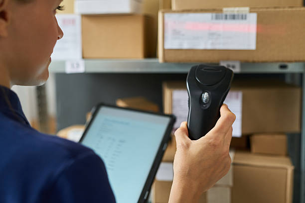 istock Young Adult Caucasian Woman Scanning Packages with Barcode Reader in Warehouse 2236742625
