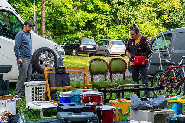 Ostrów Wielkopolski, Greater Poland Voivodeship, Poland - september 13, 2025 Flea market display of green chairs, percussion drums, radio player and bicycle, arranged near parked cars in outdoor setting.